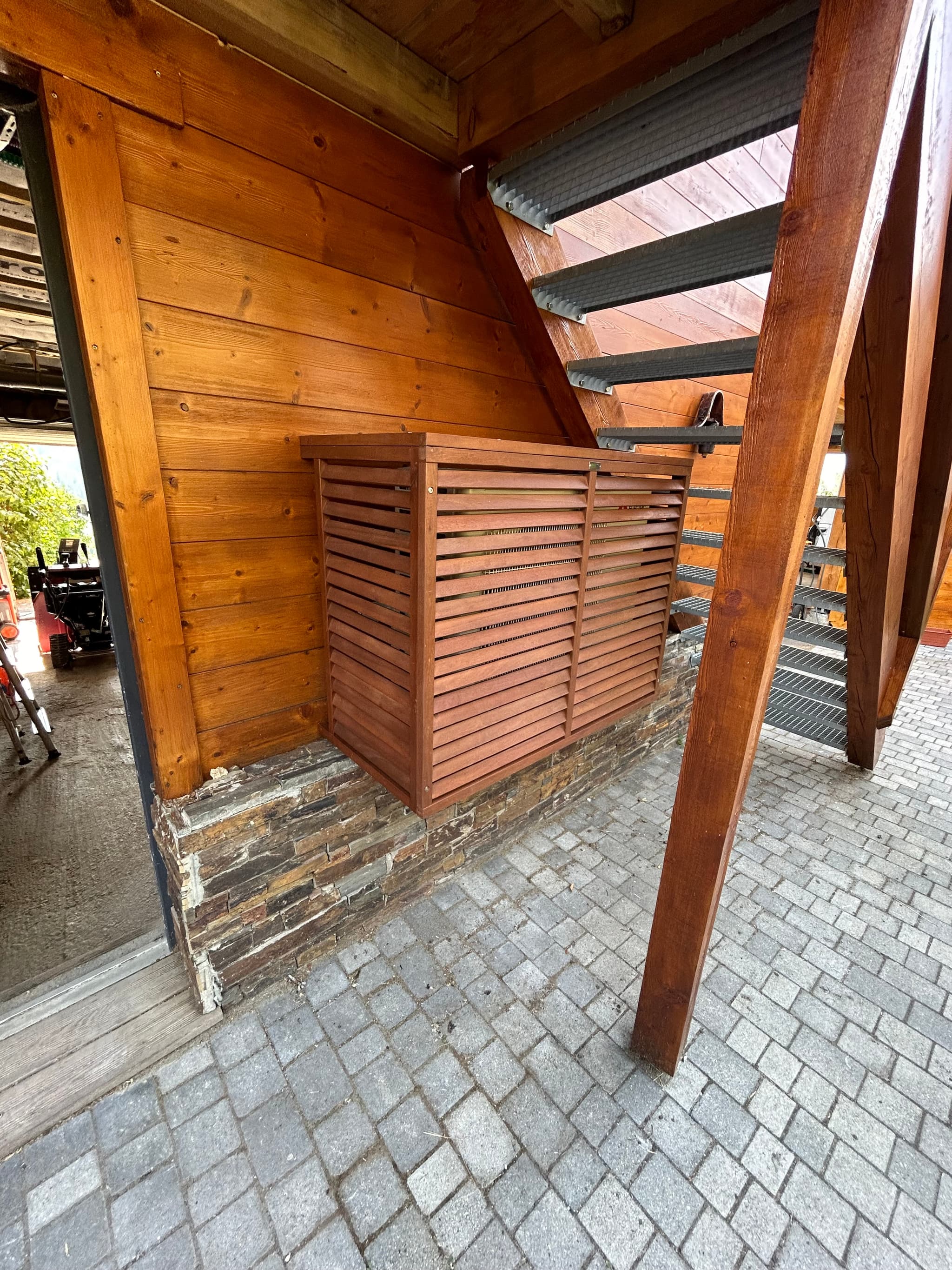 Cache en bois à claire-voie réalisé autour d'une unité extérieure, chalet à Saint-Sauveur