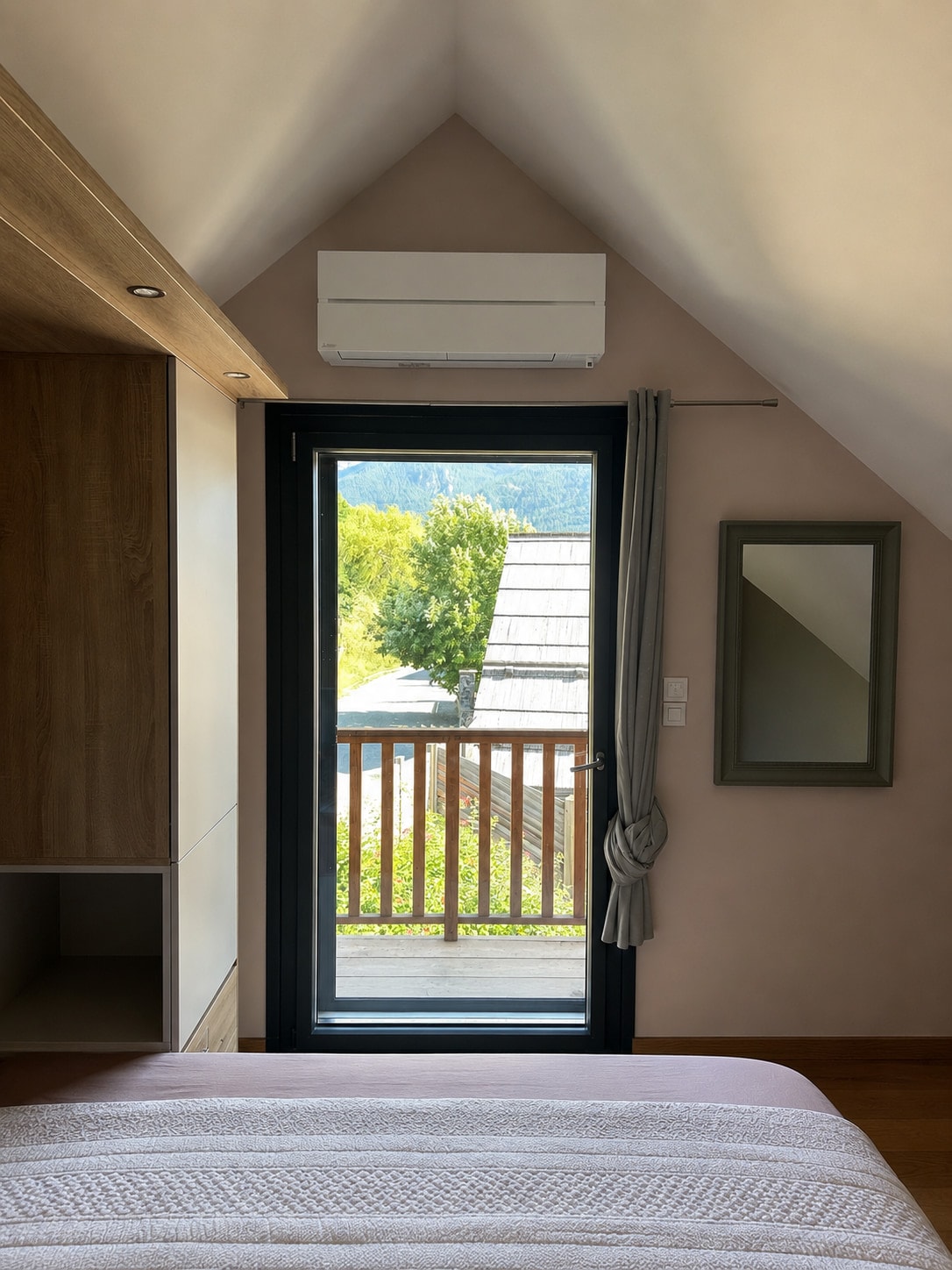 Unité intérieure murale au-dessus de la porte-fenêtre d'une chambre mansardée, chalet à Saint-Sauveur
