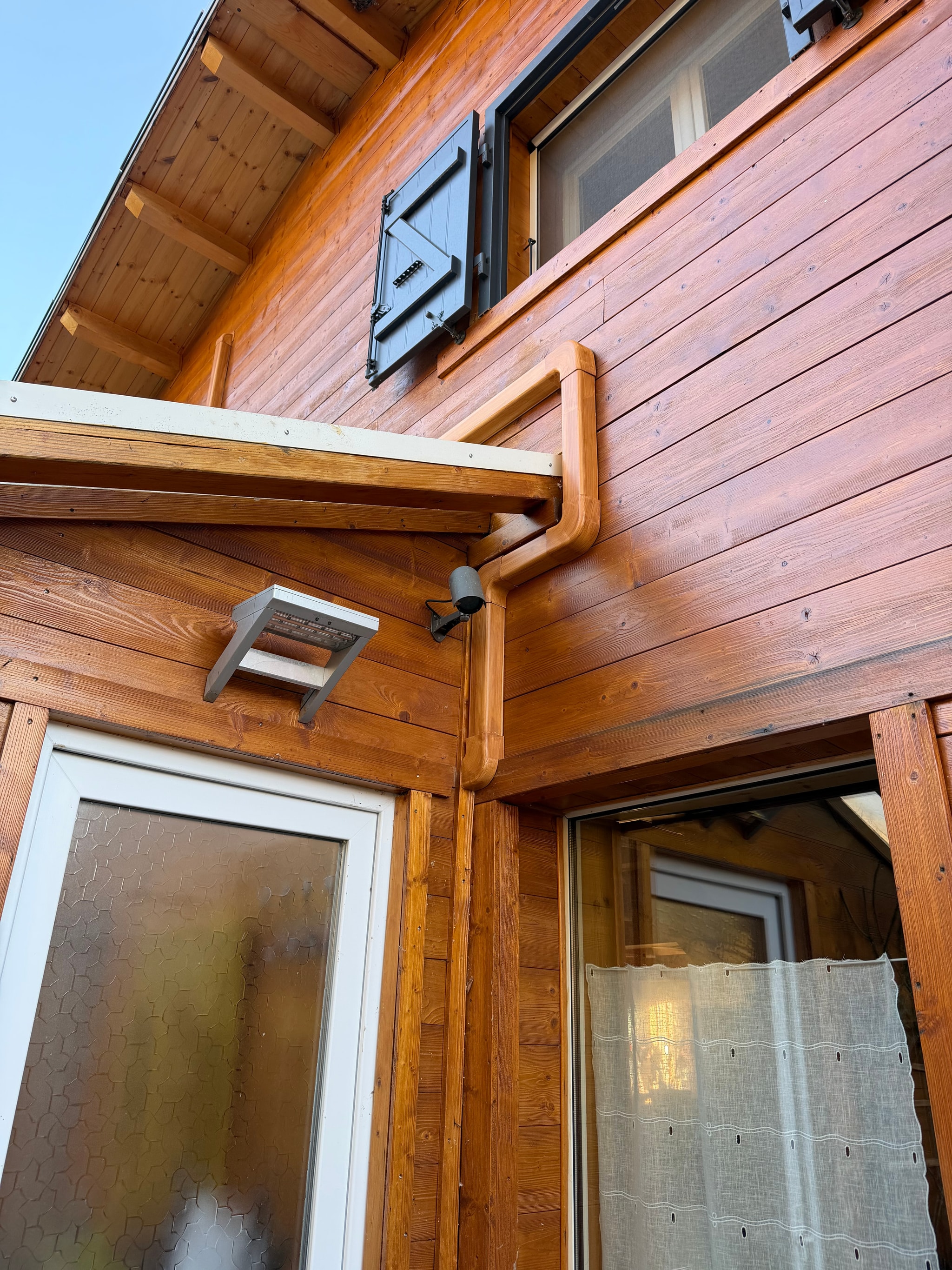 Goulottes peintes couleur bois cheminant sous l'avant-toit du chalet