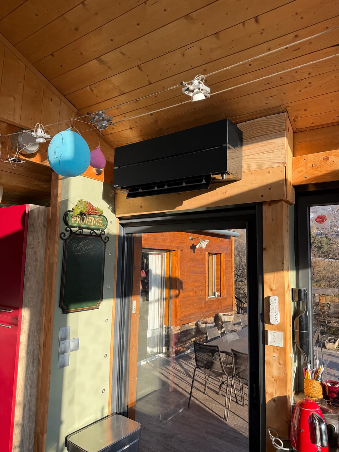 Console de climatisation noire installée au-dessus d'une baie vitrée de cuisine
