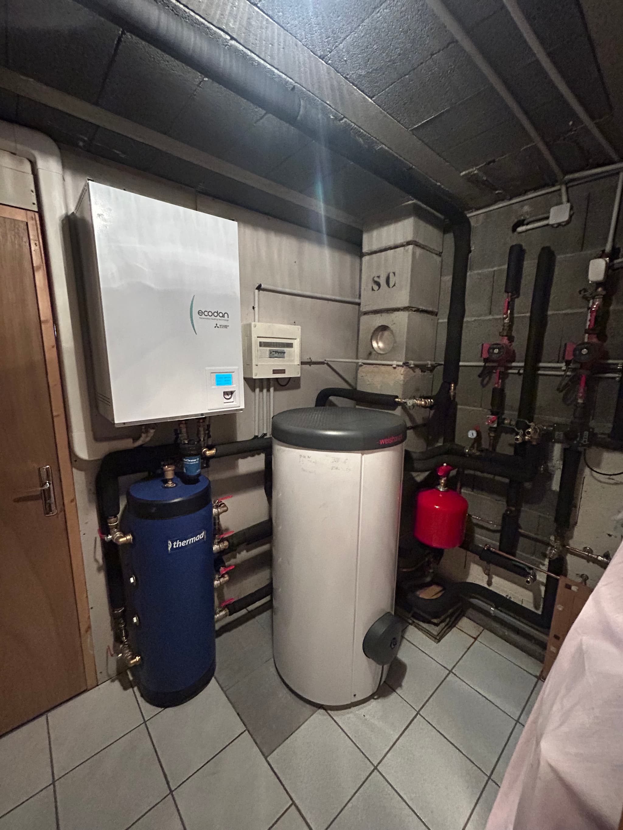 Local technique d'une maison à Briançon : module intérieur de pompe à chaleur, ballon et réseau hydraulique