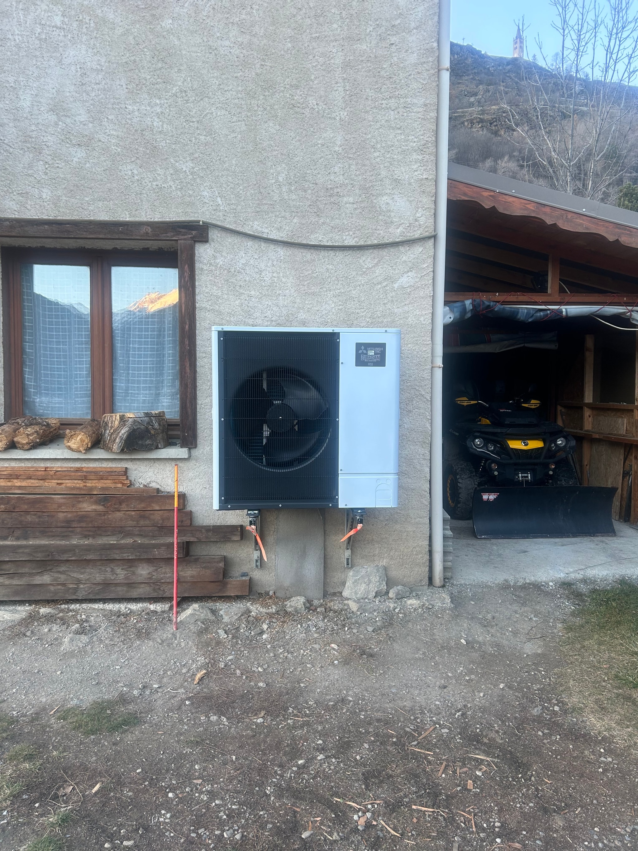 Unité extérieure de la pompe à chaleur air/eau contre le mur crépi, maison à Briançon