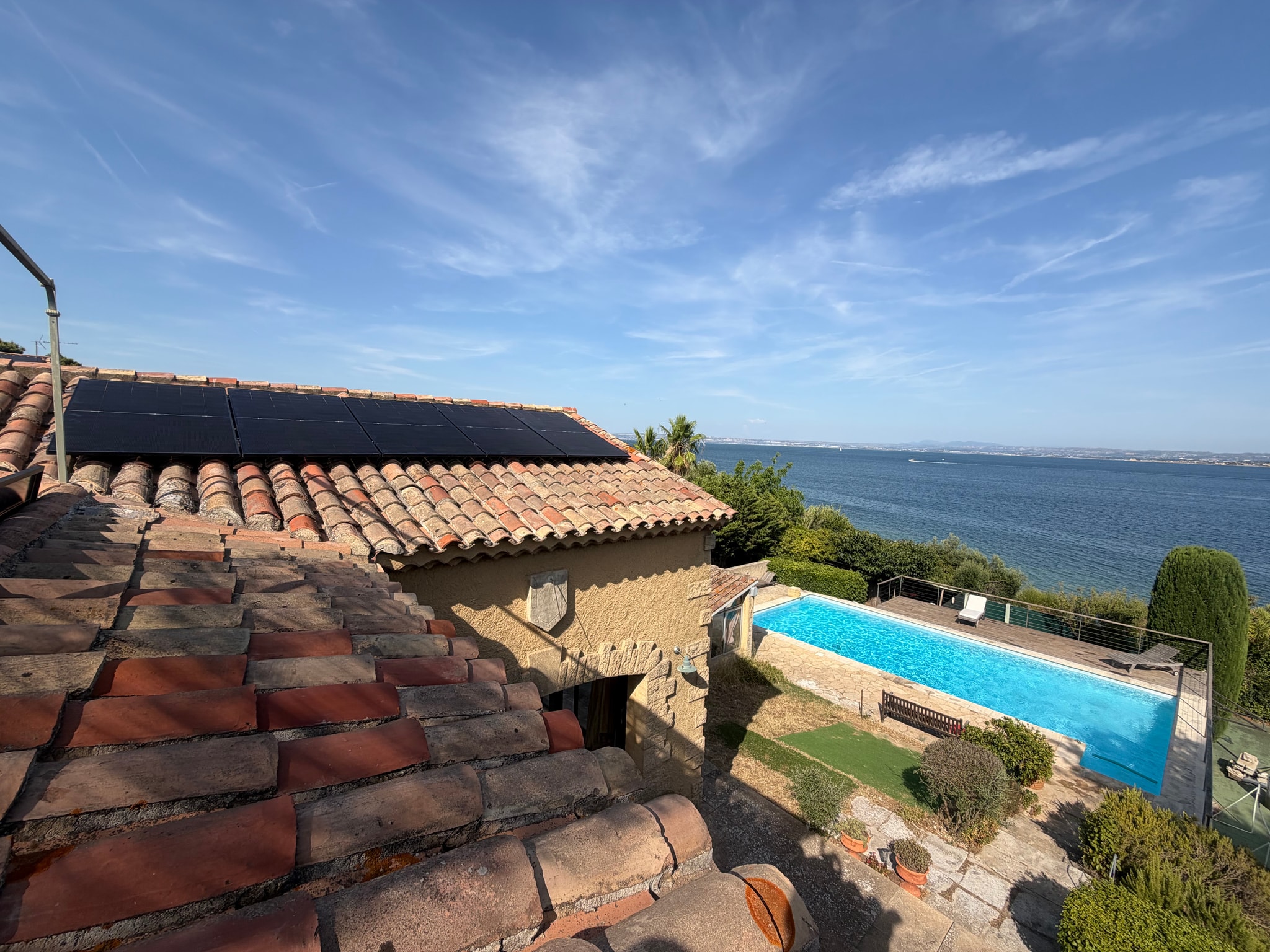Panneaux photovoltaïques sur la toiture d'une villa à Martigues, piscine et eau en contrebas