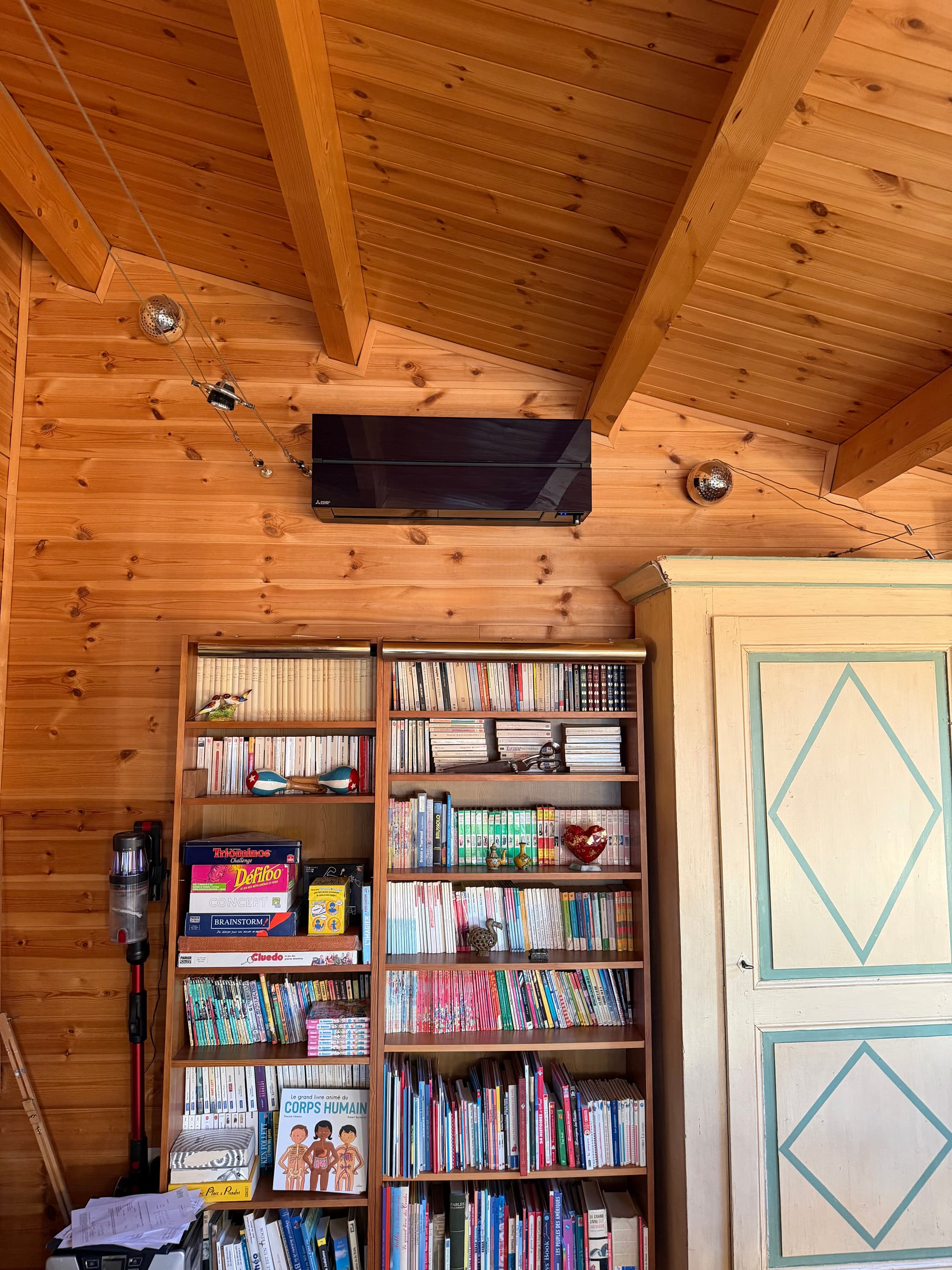 Unité murale installée dans le séjour d'un chalet à Saint-Sauveur, au-dessus d'une bibliothèque